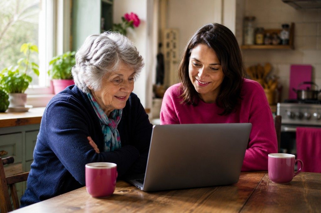 Two women look at a laptop together at a kitchen table